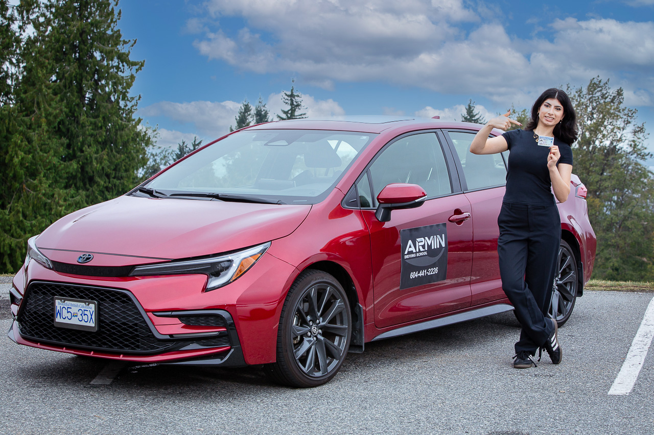 Successful Armin Driving School student beside a red training car in Metro Vancouver